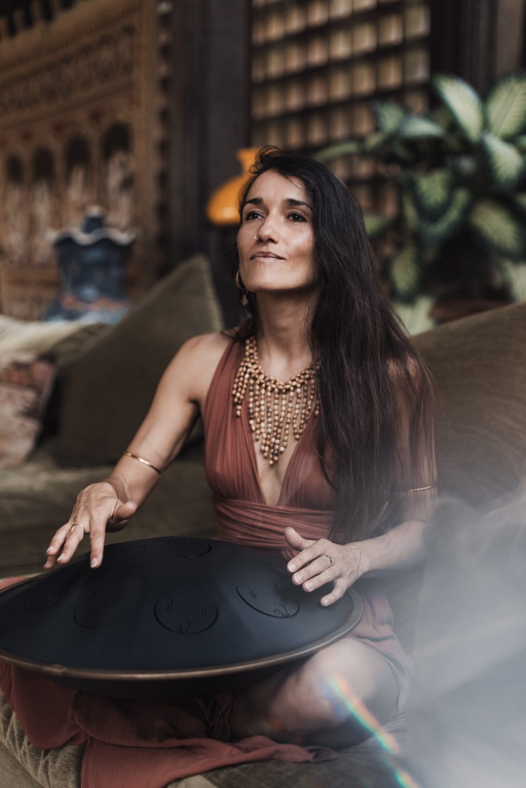 Pao Pamaki playing handpan on a couch indoors